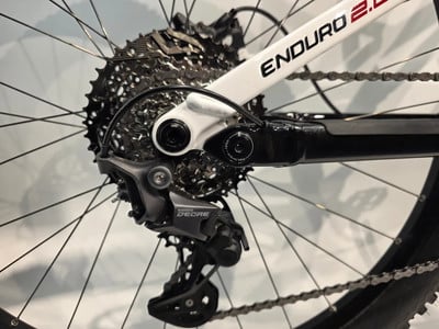 Shimano Deore Schaltwerk an weißem Enduro-Fahrradrahmen. Shimano Deore Schaltwerk an weißem Enduro-Fahrradrahmen.