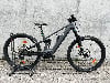Ein graues Conway E-Bike mit Federung steht auf einem Gehweg vor einer Wand.