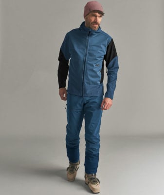 Ein Mann in blauer Skibekleidung und rosafarbener Mütze steht vor grauem Hintergrund. Ein Mann in blauer Skibekleidung und rosafarbener Mütze steht vor grauem Hintergrund.