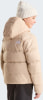 Mädchen in einer beigen Daunenjacke und Strickmütze mit The North Face Logo.