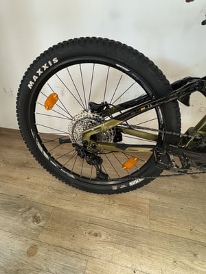 Hinterrad eines Mountainbikes mit Maxxis-Reifen und Shimano-Schaltwerk auf Holzboden.