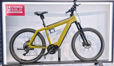 Ein gelbes Riese & Müller E-Bike mit Federung auf einem Ständer. Ein gelbes Riese & Müller E-Bike mit Federung auf einem Ständer.