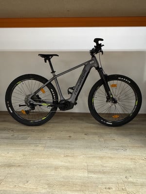Graues Genesis E-Bike mit schwarzen Rädern auf Holzboden. Graues Genesis E-Bike mit schwarzen Rädern auf Holzboden.