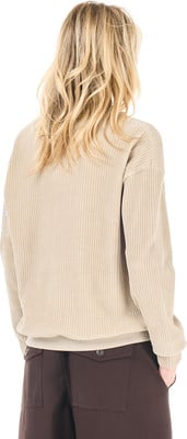 Frau mit langen blonden Haaren in beige Cord-Pullover und brauner Hose. Frau mit langen blonden Haaren in beige Cord-Pullover und brauner Hose.
