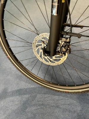 Detail eines Fahrradvorderrads mit Scheibenbremse und Gabel.