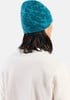 Ein Mann mit langen Haaren trägt eine blaue Strickmütze und einen weißen Pullover.