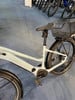 Ein hellgraues Specialized E-Bike mit Korb und Schutzblechen auf Teppich.