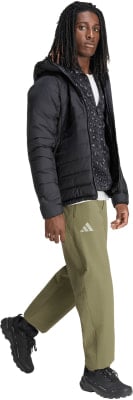 Ein Mann in schwarzer Daunenjacke und grüner Hose mit Adidas-Logo. Ein Mann in schwarzer Daunenjacke und grüner Hose mit Adidas-Logo.