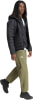 Ein Mann in schwarzer Daunenjacke und grüner Hose mit Adidas-Logo.