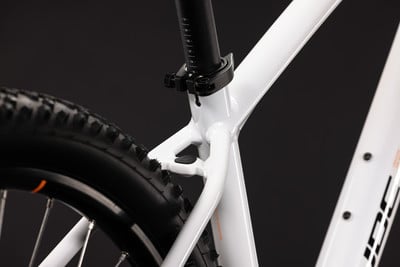 Detail des weißen Mountainbike-Rahmens mit Nahaufnahme der Sattelstütze und des Hinterrads.