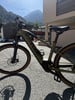 Ein grünes E-Bike, das vor einem Geschäft mit Bergen im Hintergrund geparkt ist.