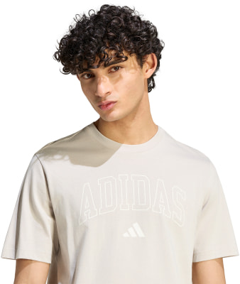 Ein Mann in einem grauen T-Shirt mit Adidas-Logo und Schriftzug. Ein Mann in einem grauen T-Shirt mit Adidas-Logo und Schriftzug.