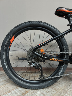 Hinterrad eines schwarzen Fahrrads mit orangefarbenen Details und Kette.