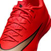 Červená futbalová obuv Nike s čierno-zlatým logom.