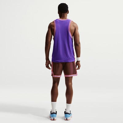 Ein Mann von hinten in einem lila Trikot und brauner Hose mit weißen Socken.