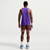 Ein Mann von hinten in einem lila Trikot und brauner Hose mit weißen Socken.