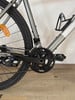 Es zeigt einen Teil eines Fahrrads mit Kette, Kurbel und Pedal auf Holzboden.
