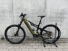 Ein goldenes E-Mountainbike der Marke Genesis steht vor einer Betonwand.