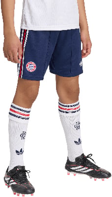 Ein Kind in dunkelblauen Shorts mit Streifen, weißen Socken und Fußballschuhen.