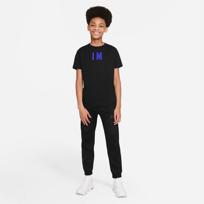 Junge in schwarzem T-Shirt mit Aufdruck IM und schwarzer Jogginghose. Junge in schwarzem T-Shirt mit Aufdruck IM und schwarzer Jogginghose.