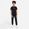 Junge in schwarzem T-Shirt mit Aufdruck IM und schwarzer Jogginghose.