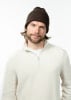 Ein Mann in einer braunen Mütze und einem beigefarbenen Pullover mit Reißverschluss.