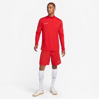 Ein Mann in einem roten Trikot und Shorts mit weißen Socken und Fußballschuhen.