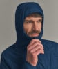 Ein Mann in einer dunkelblauen Kapuzenjacke zieht den Kragen mit der Hand zurecht.