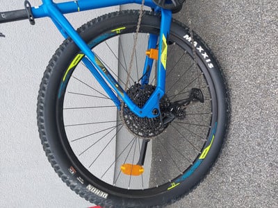 Ein blaues Mountainbike mit schwarzen Rädern und gelben Details am Rahmen. Ein blaues Mountainbike mit schwarzen Rädern und gelben Details am Rahmen.