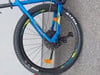 Ein blaues Mountainbike mit schwarzen Rädern und gelben Details am Rahmen.