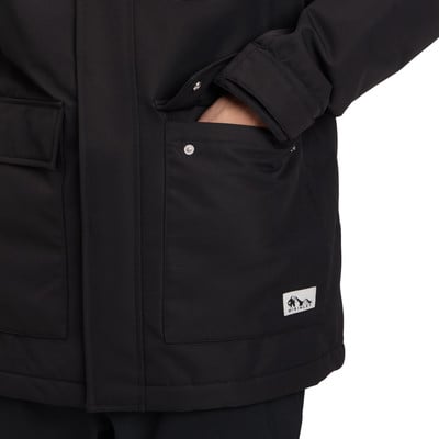 Detail einer schwarzen Jacke mit einer Tasche, in die eine Hand hineingesteckt ist. Detail einer schwarzen Jacke mit einer Tasche, in die eine Hand hineingesteckt ist.
