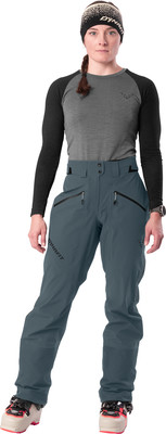 Eine Frau in Skihose und Mütze steht in Skischuhen. Eine Frau in Skihose und Mütze steht in Skischuhen.