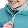 Ein Mädchen schließt ihre blaugrüne Jacke mit einem weißen Reißverschluss am Hals.
