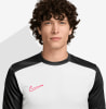 Egy férfi fehér pólóban, fekete ujjakkal és piros Nike logóval.