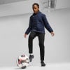 Mädchen in dunkelblauer Jacke und schwarzer Hose mit Fußball.