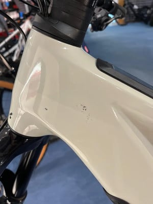 Detail eines Fahrradrahmens mit kleinen Kratzern auf der weißen Oberfläche. Detail eines Fahrradrahmens mit kleinen Kratzern auf der weißen Oberfläche.
