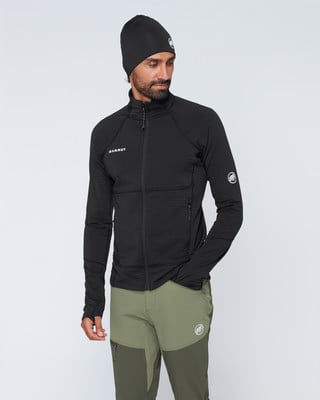 Mann in schwarzem Fleece und grüner Hose mit Mammut-Logo. Mann in schwarzem Fleece und grüner Hose mit Mammut-Logo.
