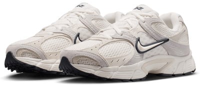 Fehér Nike cipők bézs és szürke részletekkel, fekete talppal. Fehér Nike cipők bézs és szürke részletekkel, fekete talppal.