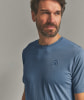 Mann in blauem T-Shirt mit gesticktem Mützensymbol.