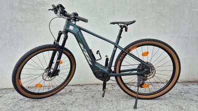 Ein grünes E-Bike mit braunen Rädern und schwarzem Rahmen steht vor einer Wand. Ein grünes E-Bike mit braunen Rädern und schwarzem Rahmen steht vor einer Wand.