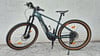 Ein grünes E-Bike mit braunen Rädern und schwarzem Rahmen steht vor einer Wand.