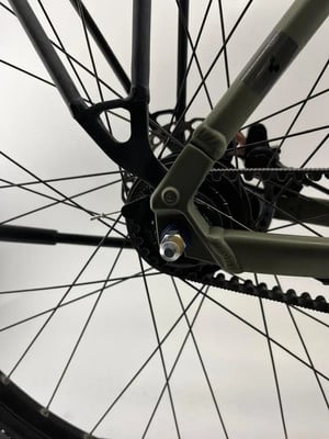 Detail eines Fahrradhinterrads mit Riemenantrieb und Mutter.