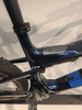 Detail des Rahmens eines dunkelblauen Mountainbikes mit Kette und Pedal.