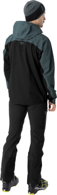 Ein Mann in Skibekleidung mit Mütze, Jacke und Hose, von hinten gesehen.