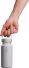 Eine Hand hält eine helle Hydro Flask Flasche am Griff.