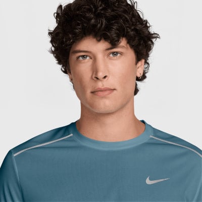 Ein Mann mit lockigem Haar in einem blauen Nike-T-Shirt. Ein Mann mit lockigem Haar in einem blauen Nike-T-Shirt.