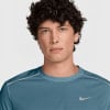 Ein Mann mit lockigem Haar in einem blauen Nike-T-Shirt.