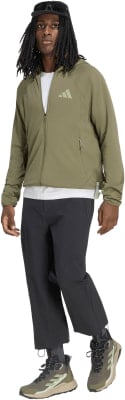 Mann in grüner Kapuzenjacke und schwarzer Hose vor weißem Hintergrund.