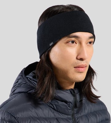 Ein Mann mit langen Haaren trägt ein schwarzes Stirnband und eine Daunenjacke.