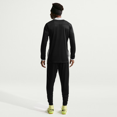 Ein Mann in schwarzer Sportkleidung mit weißem Kragen und gelben Fußballschuhen. Ein Mann in schwarzer Sportkleidung mit weißem Kragen und gelben Fußballschuhen.